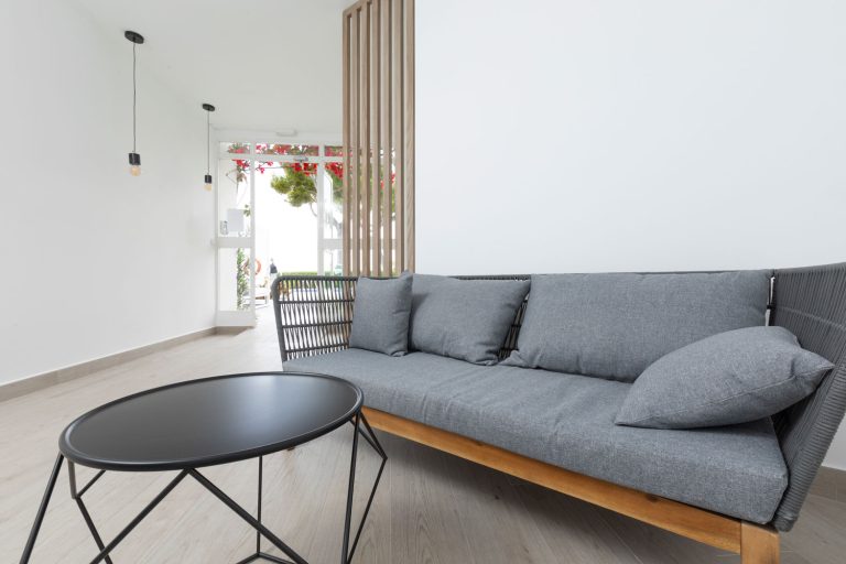 salon de la entrada de los apartamentos Leomar Sandbeach con un sofà de corte moderno con tapiceria en gris